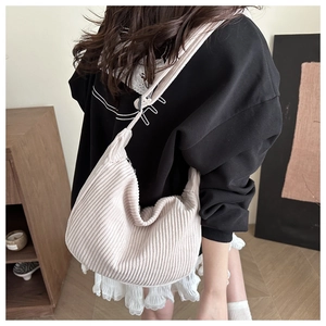 Detail of cream corduroy crossbody bag showing soft ribbed texture and crescent shape on model
