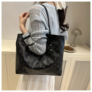 Close-up of black leather tote bag with bear print and litchi grain texture