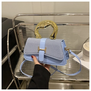 Detail of light blue handbag with gold lava-textured handle and H-shaped buckle