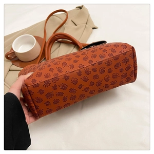 Detailed view of caramel tote bag featuring clover embossing and textured leather finish