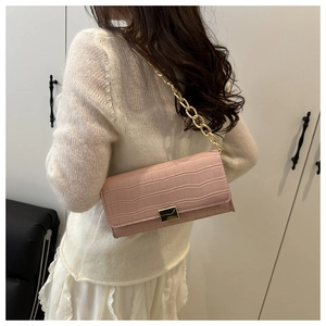 Détail du sac à bandoulière rose motif crocodile avec chaîne dorée sur un modèle