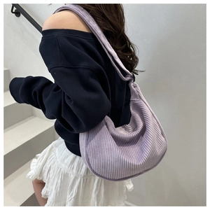 Detail view of the soft purple corduroy hobo bag texture and wide strap on model
