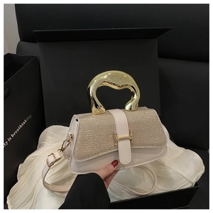 Detail view of cream leather bag with gold sequined flap and unique curved metal handle