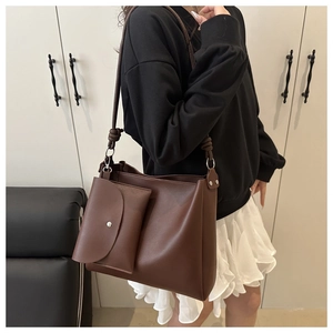 Detail view of large dark brown tote bag featuring matte leather texture and small pouch