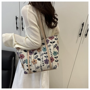 Floral tapestry tote bag with beige leather shoulder strap shown on a model