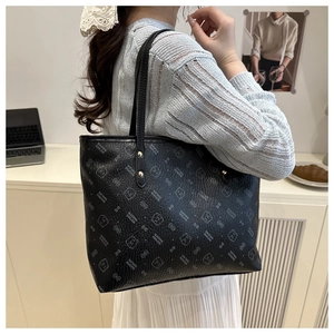Detail of black pebbled leather tote with printed patterns and gold metal buckles