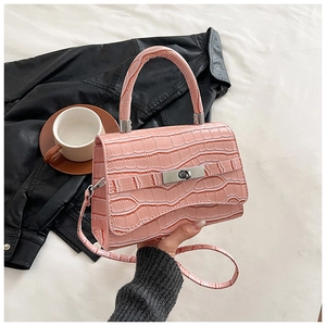 Close-up of pink faux-crocodile leather texture and silver metal twist lock on a handbag