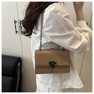 Close-up of light brown crossbody bag with crocodile texture and metal chain strap