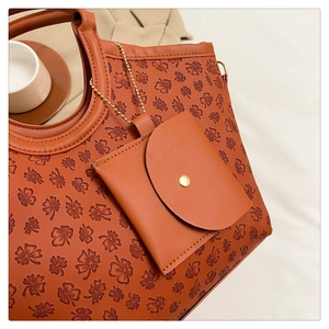 Detail of clover embossed leather tote bag with small matching circular charm and gold chain