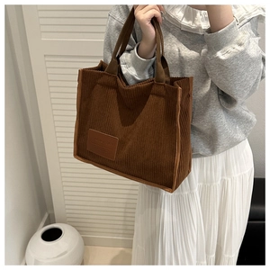 Detail view of caramel brown corduroy tote bag with fashion patch and woven handles