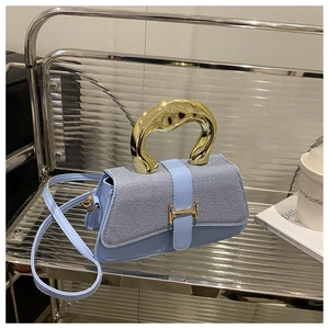 Detail of light blue denim box bag with gold H-buckle and unique metal handle