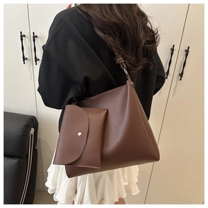 Detail of dark brown leather bucket bag with knotted strap and small pouch on shoulder