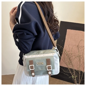 Detail van mintgroene en crème crossbodytas met lederen riempjes en konijnenlabel