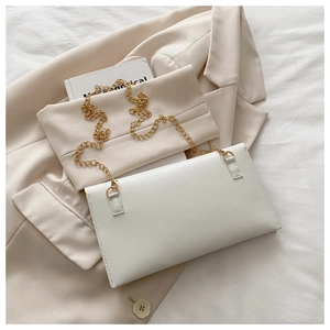 Macro shot of minimalist white envelope bag with smooth leather and gold chain detail
