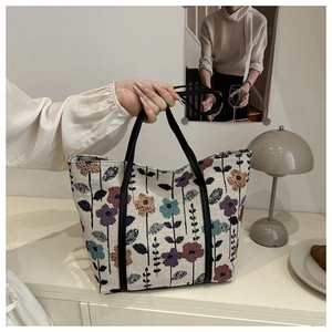 Close-up of large floral tote bag with textured weave and premium black leather handles