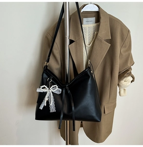 Detail of black matte PU leather tote with lace pearl bow charm and minimalist straps