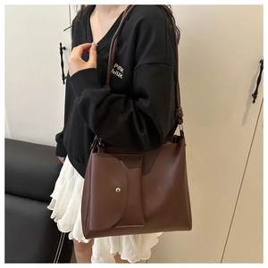 Detail of dark brown leather tote bag featuring a detachable matching coin purse charm