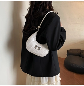 Detail of white woven crescent bag with silver metallic bow and slim shoulder strap