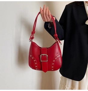 Detail of red crescent underarm bag with silver metal eyelets and knotted strap detail