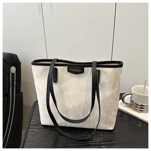 Detailed macro view of the cream tote bag texture with black trim and fashion patch