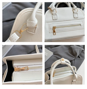 Detailed view of white litchi pattern leather with gold hardware on a Boston bag