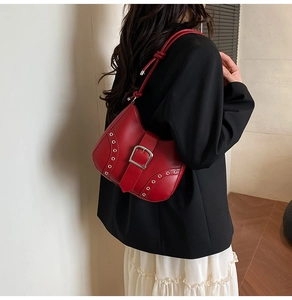 Detail of red vintage underarm bag with silver buckle and rivets on model