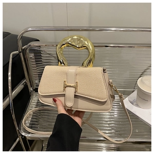 Detail of the unique gold metal circular handle and H-shaped clasp on a beige leather bag
