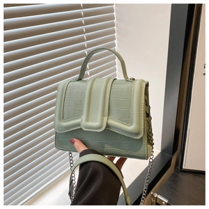 Détail du sac à main vert sauge texture crocodile avec chaîne argentée et poignée