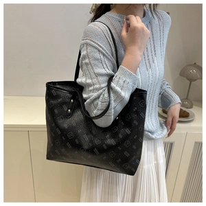 Detail shot of black leather tote bag with bear print and spacious interior for commuting