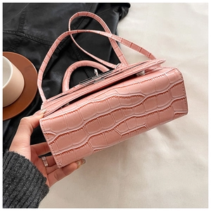 Close-up of pink crocodile texture and silver turn-lock detail on a handbag