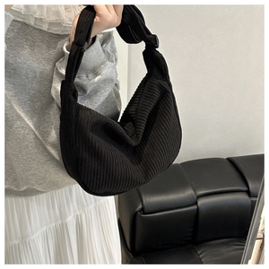 Close-up of black corduroy dumpling bag with stylish knotted adjustable strap detail