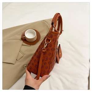 Detail of brown tote bag with clover patterns featuring a detachable coin purse and strap
