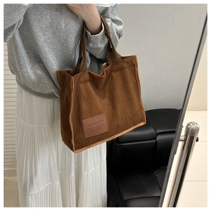 Detail of brown corduroy tote bag with fashion label and textured striped fabric