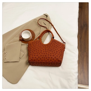 Detail of a brown tote bag featuring clover patterns and adjustable shoulder strap