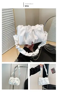 Detailed view of white shoulder bag with large bow decoration and pleated design accents