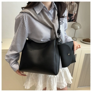 Detail of minimalist black tote bag with knot strap and small matching pouch on model