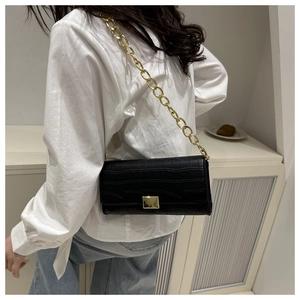 Détail d'un sac à main en cuir croco avec bandoulière chaîne dorée sur mannequin