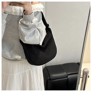 Detail of a black corduroy crescent bag shown in a lifestyle mirror selfie context