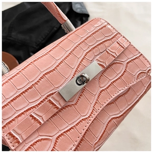 Detail shot of pink crocodile texture leather and silver metal twist lock on handbag