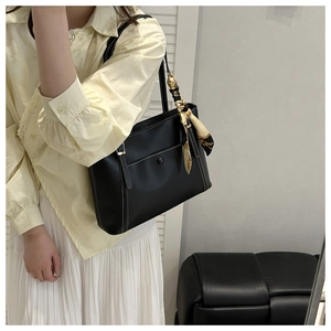 Détail du cabas en cuir noir avec surpiqûres contrastées et foulard floral à la poignée
