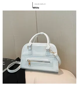 Close-up of white lychee pattern leather shell bag with gold zippers and detachable strap