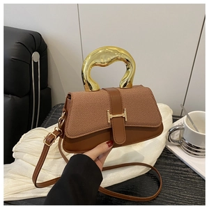 Detail of a brown textured crossbody bag featuring a unique gold metal handle and clasp