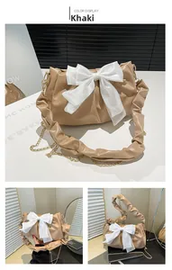 Detail of khaki PU leather handbag featuring pleated texture and large white bow