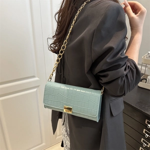 Sac à bandoulière vert clair effet crocodile avec chaîne dorée sur blazer noir