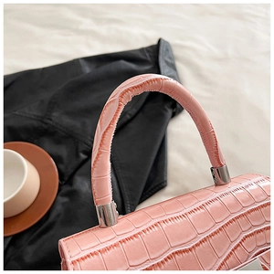 Detailed close-up of pink crocodile texture handbag with silver metal hardware