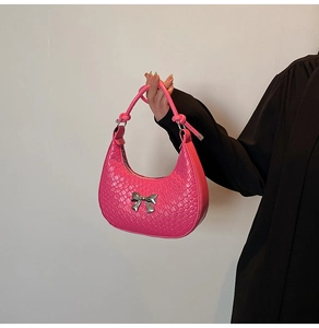 Detailed close-up of pink crescent handbag with silver bow accent and knot handle detail