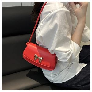 Détail d'un sac bandoulière rouge avec boucle noeud doré sur cuir synthétique