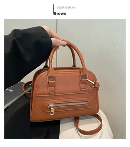 Detail view of brown lychee grain leather tote bag with gold hardware and zipper pocket