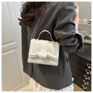 Detail of white crocodile embossed handbag with geometric flap and chain strap