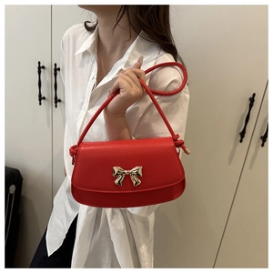 Détail d'un sac en cuir rouge avec boucle dorée en nœud et bandoulière nouée